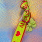 Close-up of 'Amour' text and lime green bow charm