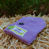 Lilac All Smiles & Happy Vibes beanie with smiley patches displayed on straw