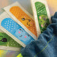 Colorful kids bandages with cute faces peeking out from the denim first aid kit pouch