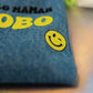 Close-up of a yellow winking smiley printed on the denim Allo Maman Bobo first aid kit pouch