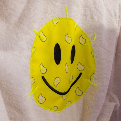 Yellow smiley face patch stitched on back of white cotton kids bathrobe