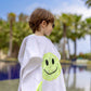 Side view of child wearing the Bandana Smiley Poncho cotton white at the poolside