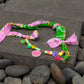 Full view of Bandana Twin Bracelet with green and pink bandana fabric and playful beads on rock surface