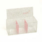 Angled view of clear glitter storage box with pink divider sections