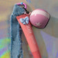 Close-up of Biker Girl Key Charm featuring pink helmet, denim strap and lip balm
