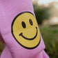 Close-up of yellow smiley face print on bubble gum pink kids fleece jogger pants