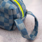 close-up of checkered denim pouch handle and neon zipper detail