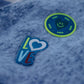 Close-up of LOVE slogan pin and smiley heart pin on navy and denim blue checkered scarf