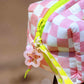 Close-up of peony pink checkered puffy pouch showing zipper and decorative pin details