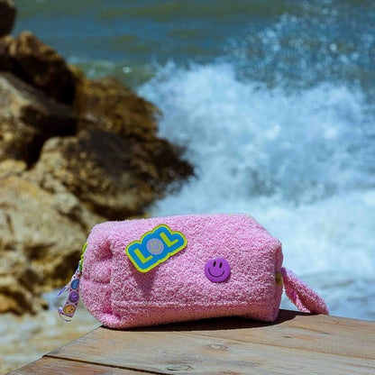 Curious Baby Pink Towel Puffy cosmetic bag displayed by the seaside