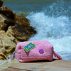 Curious Baby Pink Towel Puffy cosmetic bag displayed by the seaside