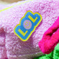 Close-up of LOL smiley patch on Curious Baby Pink Towel Puffy cosmetic bag
