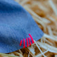 Close-up of pink thread stitching on denim scrunchie