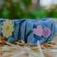 Side view of denim wavy headband with smiley flower and heart details