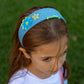 Child wearing denim wide headband with decorative flower and star