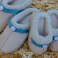 Side angle view of fluffy smiley slip-on slippers showcasing plush fur interior and smiley button detail
