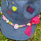close up of denim cap showing smiley beads and colourful charms