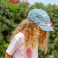 child wearing denim cap decorated with smileys and pastel beads