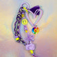 Full view of the chunky beaded keychain with a large lavender heart, purple paracord strap, neon peace sign, and rainbow flower charm