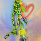 Close-up of peach heart graffiti key charm with green rope, peace sign bead and cassette charm