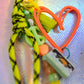 Peach graffiti heart charm detail with green tassel and peace symbol bead