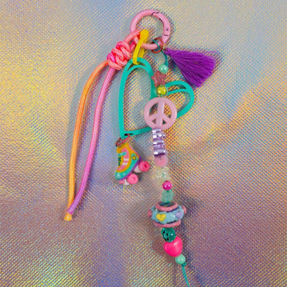 Full view of the chunky beaded keychain featuring a teal heart, neon pink and orange paracord, and a fun roller skate charm