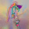 Full view of the chunky beaded keychain featuring a teal heart, neon pink and orange paracord, and a fun roller skate charm