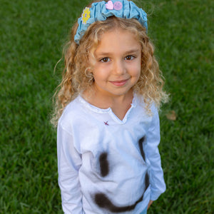 Child wearing a cotton white long sleeve T-shirt with graffiti smiley print and denim headband