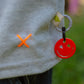 Close-up of red smiley charm attached to light grey graffiti smiley long sleeve T-shirt