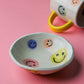 Colourful ceramic happy face bowl with multicolour smiley designs inside and smooth glazed finish