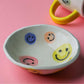 Happy face ceramic bowl with hand-painted smiley details and glossy yellow handle accent