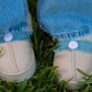Kids wearing fluffy smiley slip-on slippers with denim jeans outdoors on grass