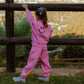 Full back view of child wearing bubble gum pink kindness is cool fleece jogger set outdoors