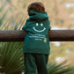 Back view of galaxy green Kindness is Cool fleece hoodie showing oversized smiley graphic and positive message print