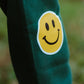 Close-up of yellow smiley face print on galaxy green fleece jogger pants for kids