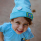 Close-up of sky blue LOL beanie with smiley pin and logo patch
