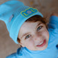 Child wearing sky blue LOL beanie with smiley badge, front view