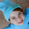 Child wearing sky blue LOL beanie with smiley badge, front view
