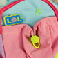Close-up of the Chunky Bag Charm, highlighting the pastel pink and blue colors of the miniature backpack, the white straps, and the silver zipper detail