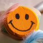 Close-up of orange smiley face bath bomb with textured fizz surface and bold black facial design