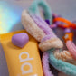 Close-up of the pastel colored fuzzy yarn tassel attachment, showing the texture and the small lavender heart accent placed on the yellow lip balm prop