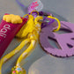 Close-up of Peace & Love Key Charm showing yellow tassel, charms, and purple peace sign