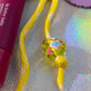 Detail shot of Peace & Love Key Charm showing yellow cord and decorative heart bead