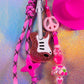 Detail showing the primary charms—the pink peace sign, the glitter guitar, and the pink cowboy hat
