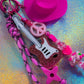 Close-up of the bright Neon Pink Cowboy Hat charm and the glittery pink electric guitar charm with a black/pink paracord strap