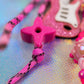 Detail of the bright magenta Ninja Star Bead acting as a cord stop, connecting to the pink and black paracord strap