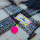Close-up of Big Dreamer stitched label and pink smiley charm on navy and bright pink plaid scarf