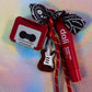 The Red Cassette Tape Charm and Red Glitter Guitar Charm shown next to the red lip balm prop