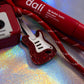 Macro shot of the Red Glitter Electric Guitar Charm, highlighting the sparkly red resin and white pickup detail