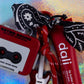 Close-up of the Retro Sound Cassette Tape Charm and the black and white paisley Bandana Charm bow attached to the bright red paracord strap